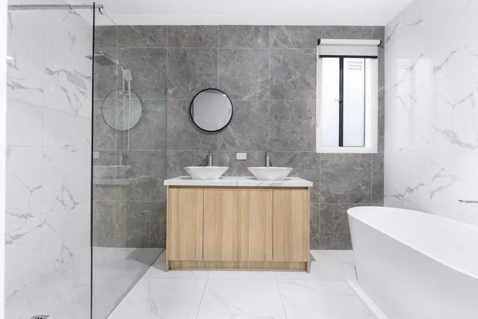 A sleek and stylish modern bathroom with minimalist design, featuring dual washbasins, marble tiles, and a glass shower enclosure.